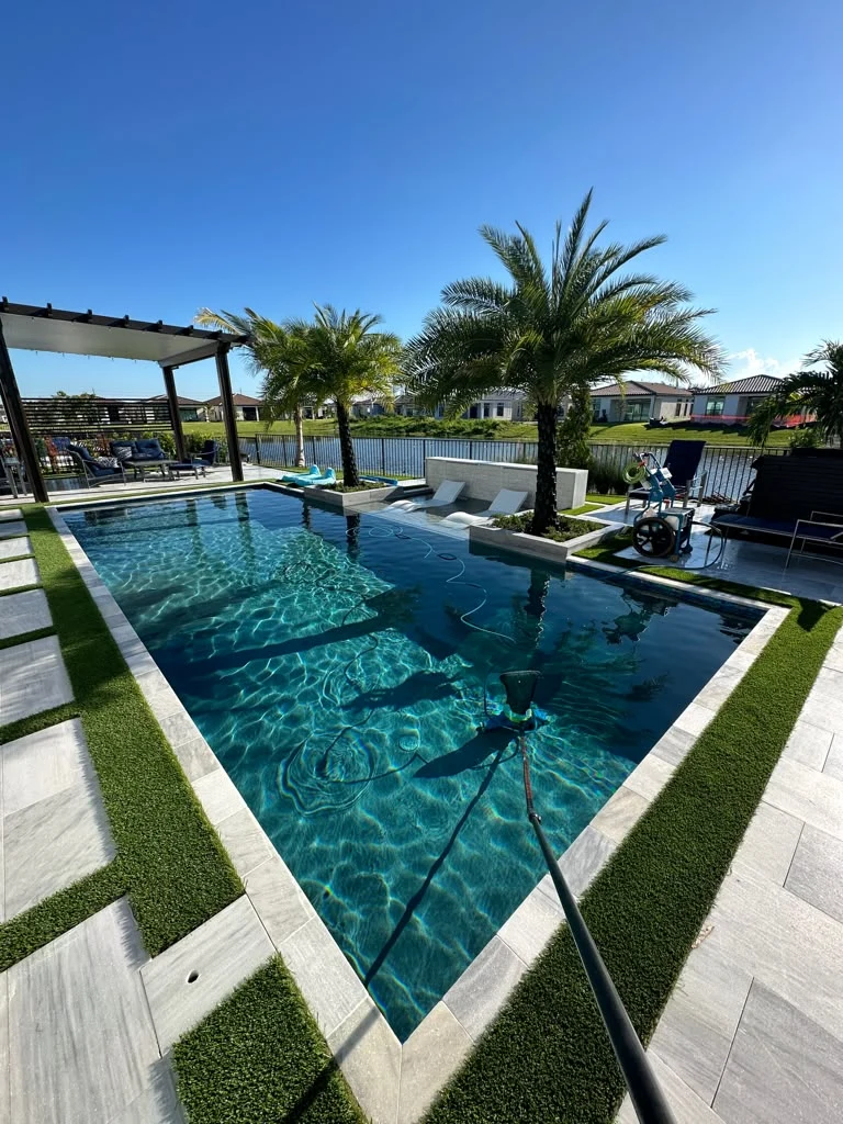 Pool maintenance in progress at a clear rectangular pool with palm trees