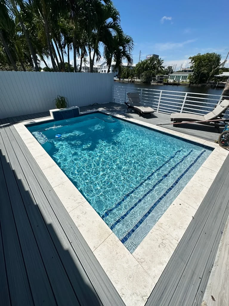 Clear swimming pool with tiled steps beside a waterfront deck